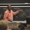 Chemistry Professor pointing to a molecular diagram on chalkboard